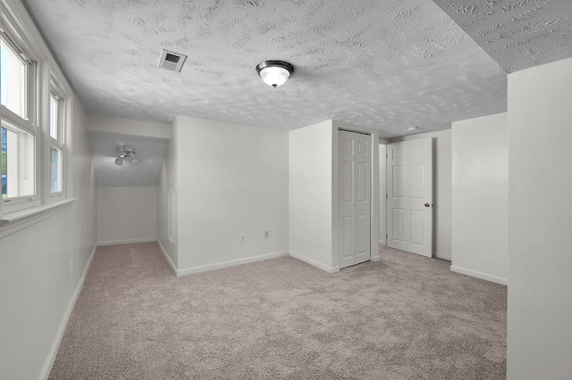 carpeted empty room with a textured ceiling