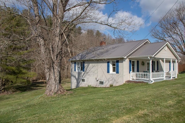view of side of home with a lawn, a porch, and a chimney