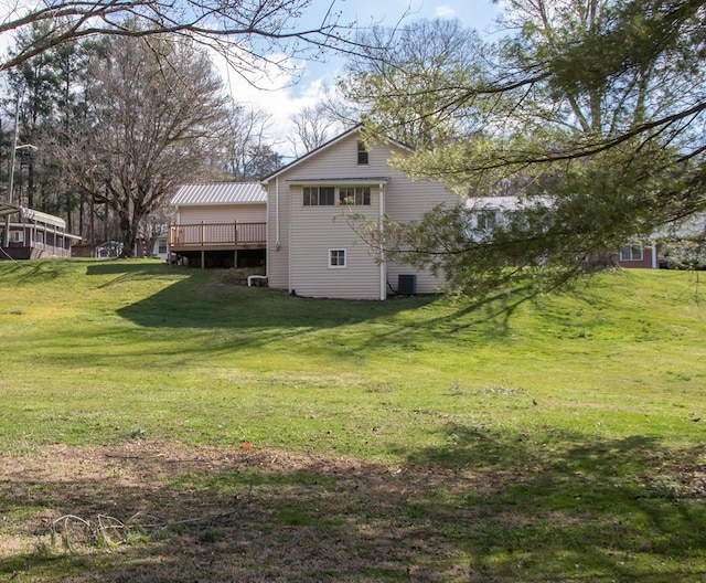 rear view of house with central AC, a wooden deck, and a yard