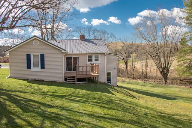 back of house featuring a wooden deck, a lawn, a chimney, and metal roof