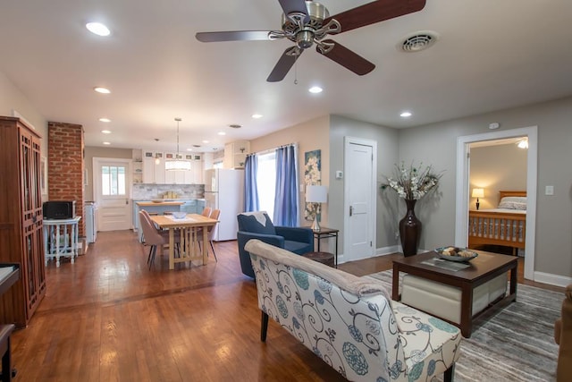 living area featuring a ceiling fan, wood finished floors, baseboards, visible vents, and recessed lighting