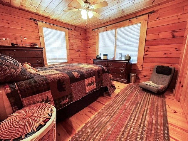 bedroom with wood ceiling, light hardwood / wood-style flooring, ceiling fan, and wood walls