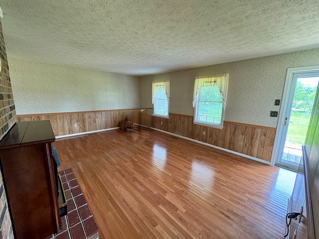 15296 Blueberry Ln, Chilhowie, VA 24319 - unfurnished living room with a textured ceiling, wood finished floors, a wainscoted wall, plenty of natural light, and wood walls