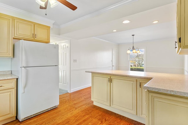 kitchen featuring light countertops, crown molding, cream cabinets, freestanding refrigerator, and light wood-style flooring