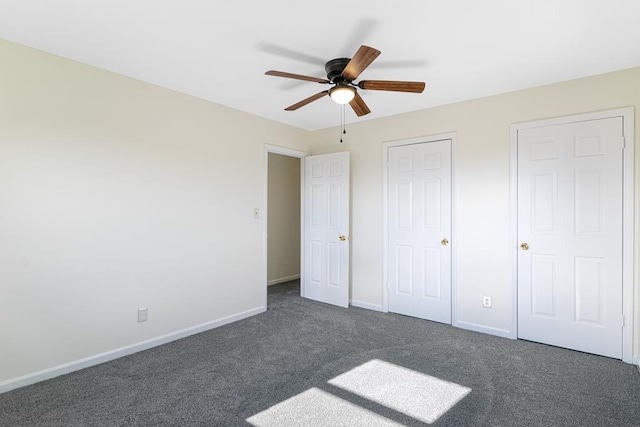 unfurnished bedroom with baseboards, dark colored carpet, and ceiling fan