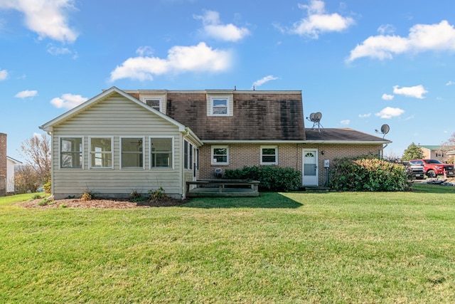 rear view of property with roof with shingles, brick siding, and a yard
