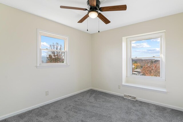 carpeted spare room featuring baseboards, visible vents, a ceiling fan, and plenty of natural light