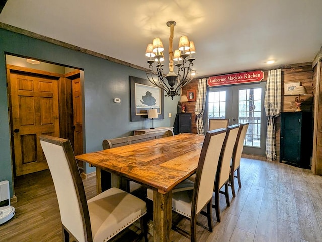 dining area featuring french doors, wood finished floors, and an inviting chandelier