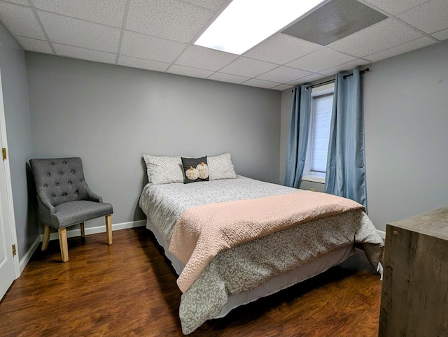 bedroom featuring wood finished floors, a paneled ceiling, and baseboards