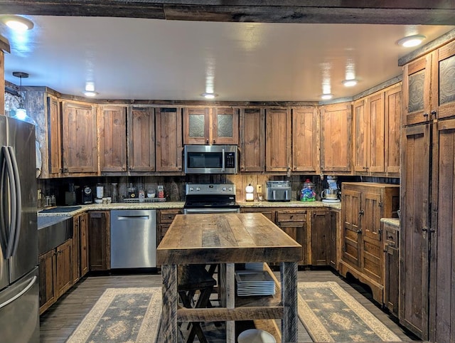 kitchen with stainless steel appliances, wood finished floors, glass insert cabinets, and decorative backsplash