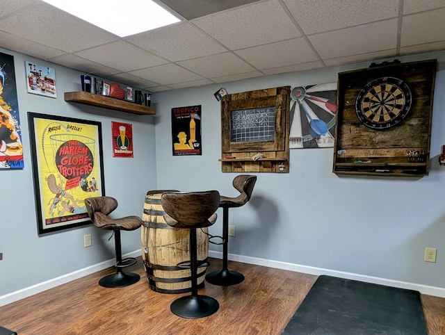 bar featuring wood finished floors, a paneled ceiling, and baseboards