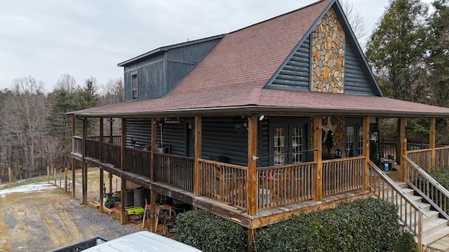 back of house featuring a porch, stairway, and a shingled roof