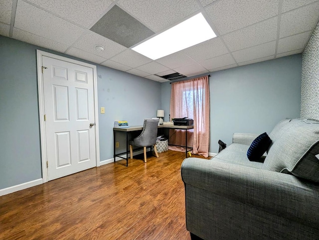 bedroom featuring a drop ceiling, wood finished floors, and baseboards