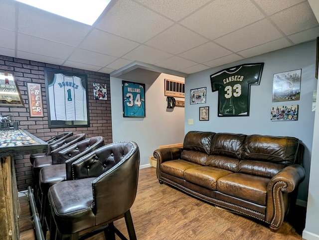 living area featuring wood finished floors, a paneled ceiling, and baseboards