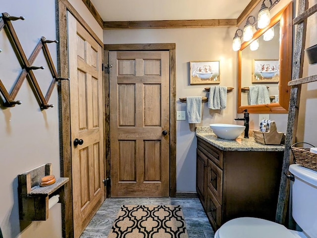 bathroom with wood finished floors, vanity, toilet, and crown molding