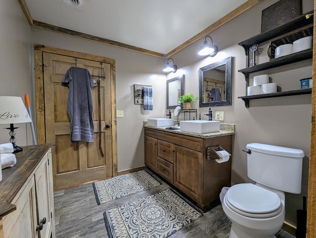 bathroom featuring wood finished floors, ornamental molding, vanity, and toilet