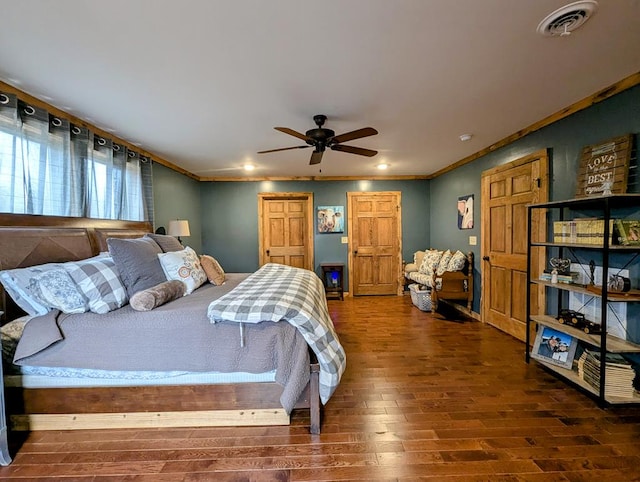 bedroom with ceiling fan, visible vents, wood finished floors, and ornamental molding