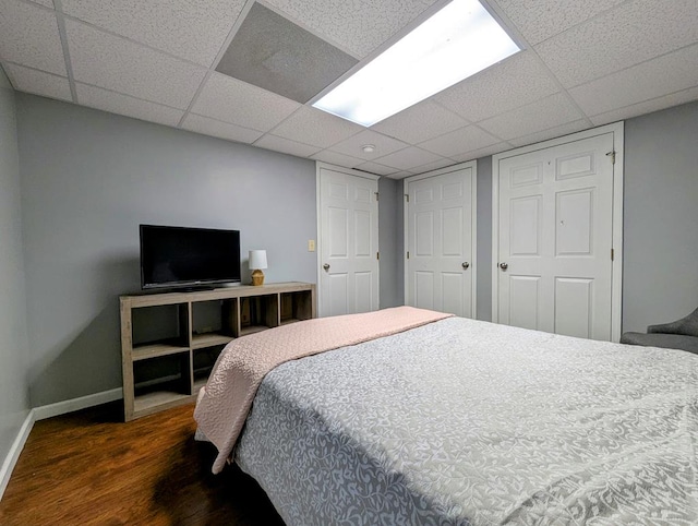 bedroom with a paneled ceiling, a closet, baseboards, and wood finished floors