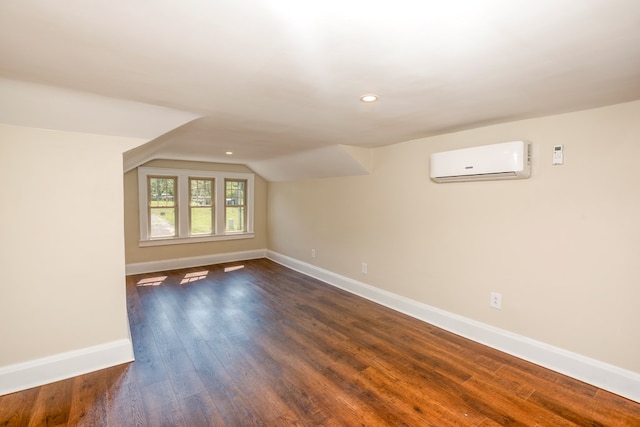 spare room featuring baseboards, lofted ceiling, recessed lighting, dark wood-type flooring, and a wall mounted air conditioner