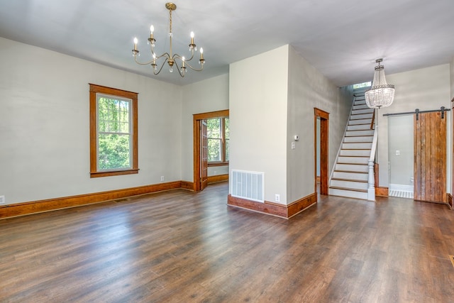 empty room featuring visible vents, stairs, a barn door, wood finished floors, and a notable chandelier