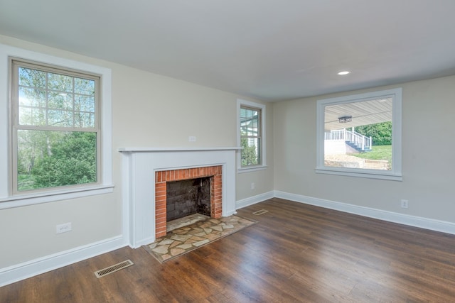 unfurnished living room with visible vents, baseboards, wood finished floors, and a fireplace