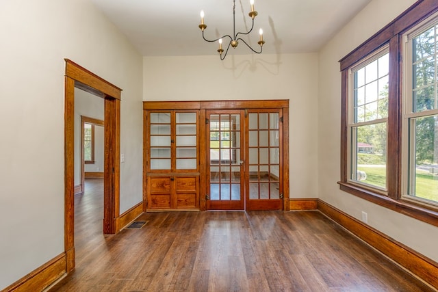 interior space featuring baseboards, a notable chandelier, and dark wood finished floors