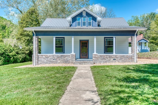 bungalow-style house with metal roof, stone siding, covered porch, and a front yard