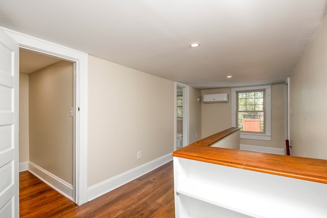 hallway featuring dark wood-type flooring, recessed lighting, baseboards, and a wall mounted air conditioner