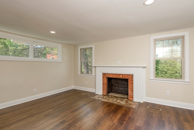 unfurnished living room featuring visible vents, baseboards, wood finished floors, and a fireplace