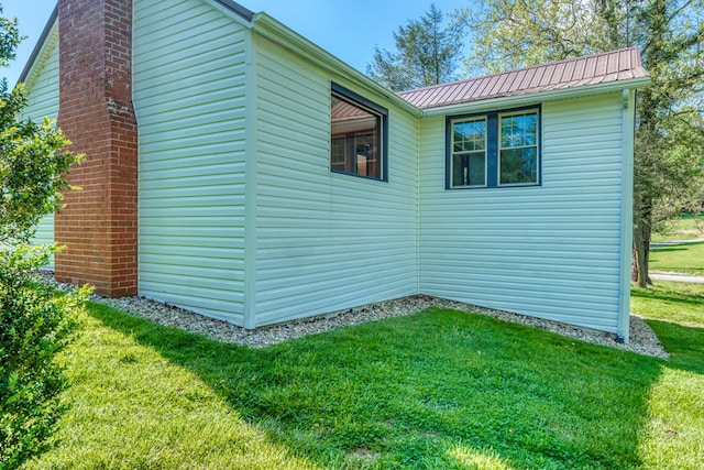 view of side of home with a chimney, a lawn, metal roof, and a standing seam roof