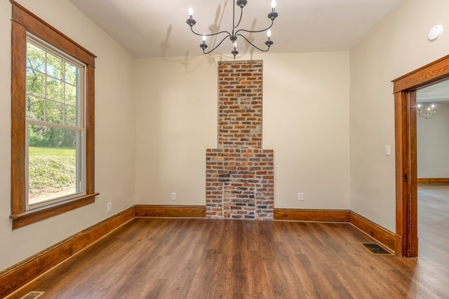 unfurnished dining area with a chandelier, visible vents, baseboards, and wood finished floors