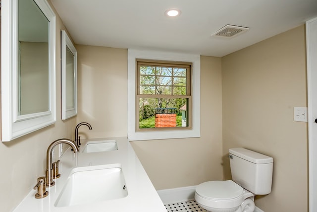 bathroom featuring visible vents, toilet, baseboards, and a sink