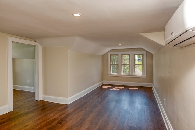 bonus room with baseboards, lofted ceiling, an AC wall unit, and dark wood-style flooring