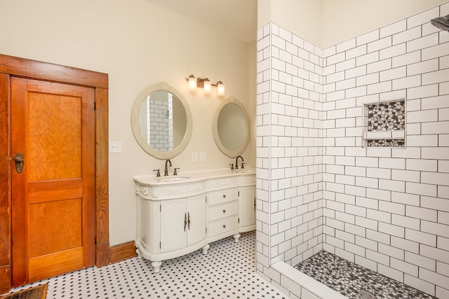 bathroom featuring a sink, tiled shower, and double vanity