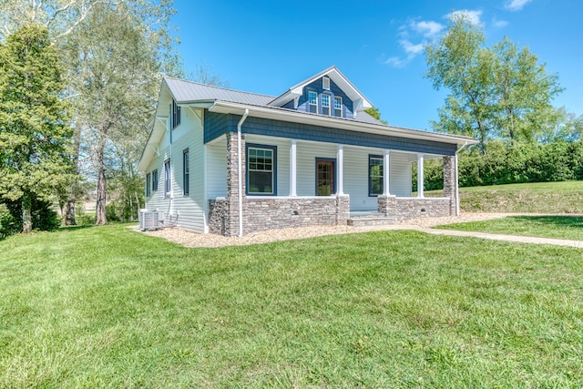 view of front of property featuring stone siding, covered porch, central AC, and a front lawn