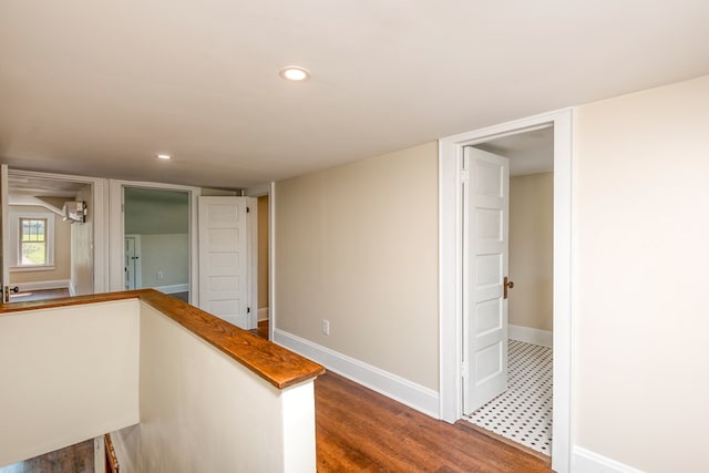 hallway with an upstairs landing, recessed lighting, baseboards, and dark wood-style flooring