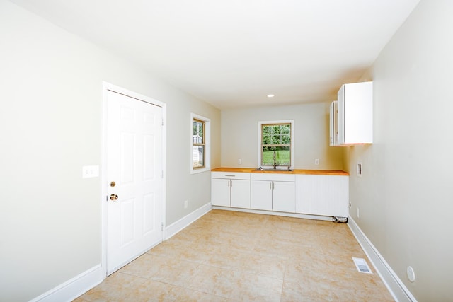 laundry room featuring cabinet space, baseboards, visible vents, and a sink