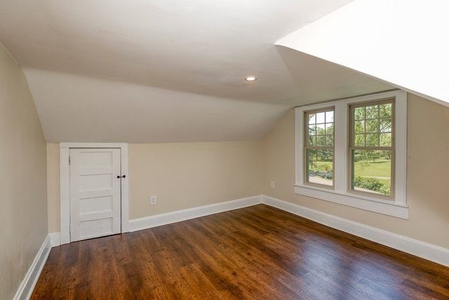 bonus room with dark wood-style floors, lofted ceiling, and baseboards