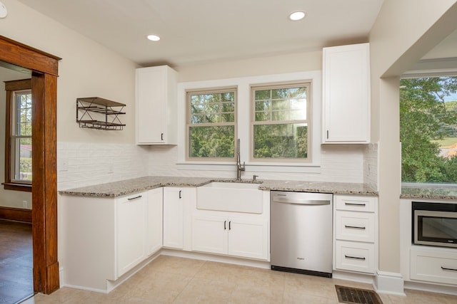 kitchen with a sink, light stone countertops, appliances with stainless steel finishes, and white cabinets