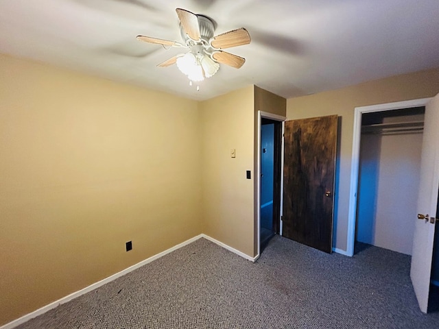 unfurnished bedroom with ceiling fan, dark carpet, and a closet