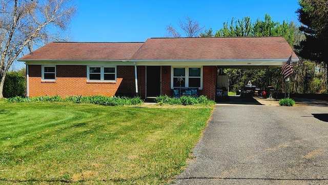 ranch-style home with brick siding, driveway, a front yard, and an attached carport