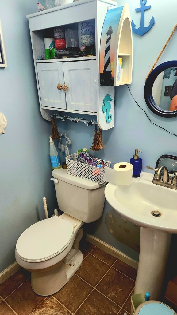 half bath featuring tile patterned flooring, toilet, and baseboards