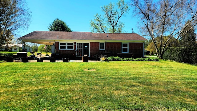 rear view of house featuring brick siding, a yard, and a patio