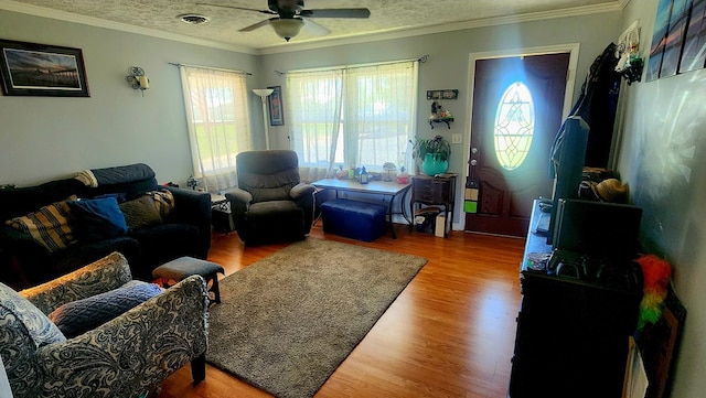 living room with ceiling fan, ornamental molding, wood finished floors, and visible vents