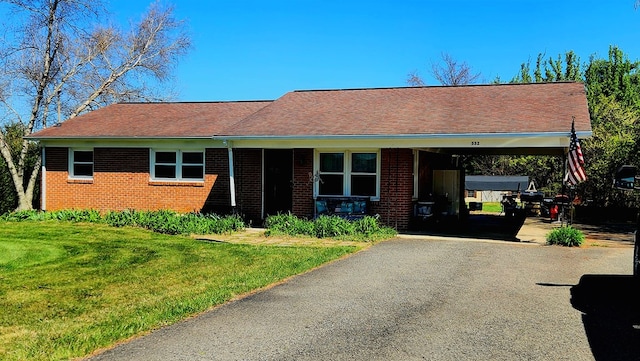 ranch-style house with brick siding, driveway, an attached carport, and a front yard