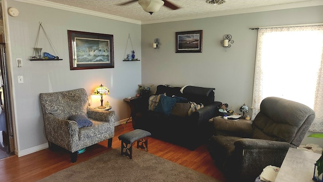 living area with crown molding, a ceiling fan, wood finished floors, and visible vents
