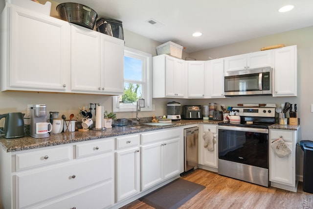 1048 Preston Dr, Radford, VA 24141 - kitchen featuring appliances with stainless steel finishes, white cabinetry, light wood-style flooring, dark stone countertops, and recessed lighting