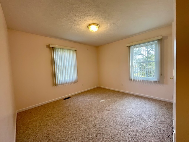 carpeted spare room with baseboards, a textured ceiling, and visible vents