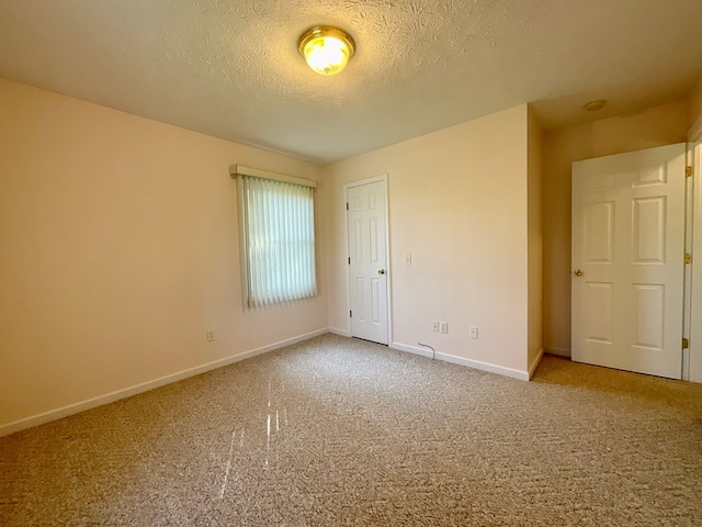 unfurnished bedroom featuring carpet, a textured ceiling, and baseboards