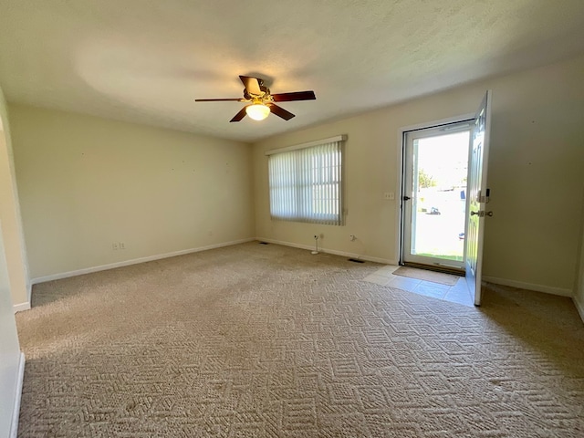 unfurnished room with baseboards, visible vents, light colored carpet, and ceiling fan